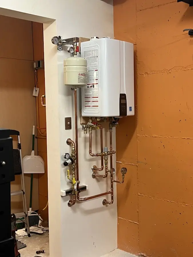 Plumbing technician inspecting water heater connections in Hope